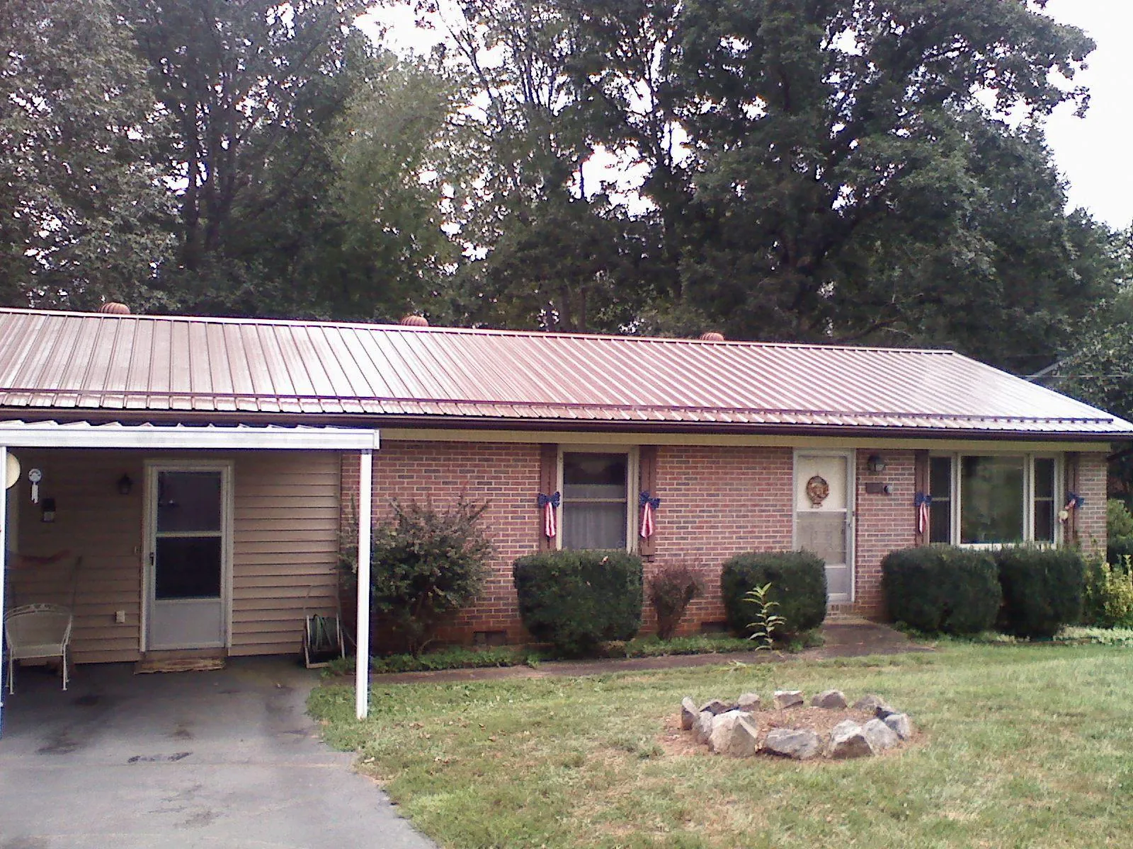 Bronze metal roof and carport on a brick ranch home — Roof Repair work by our crew in Dunlap