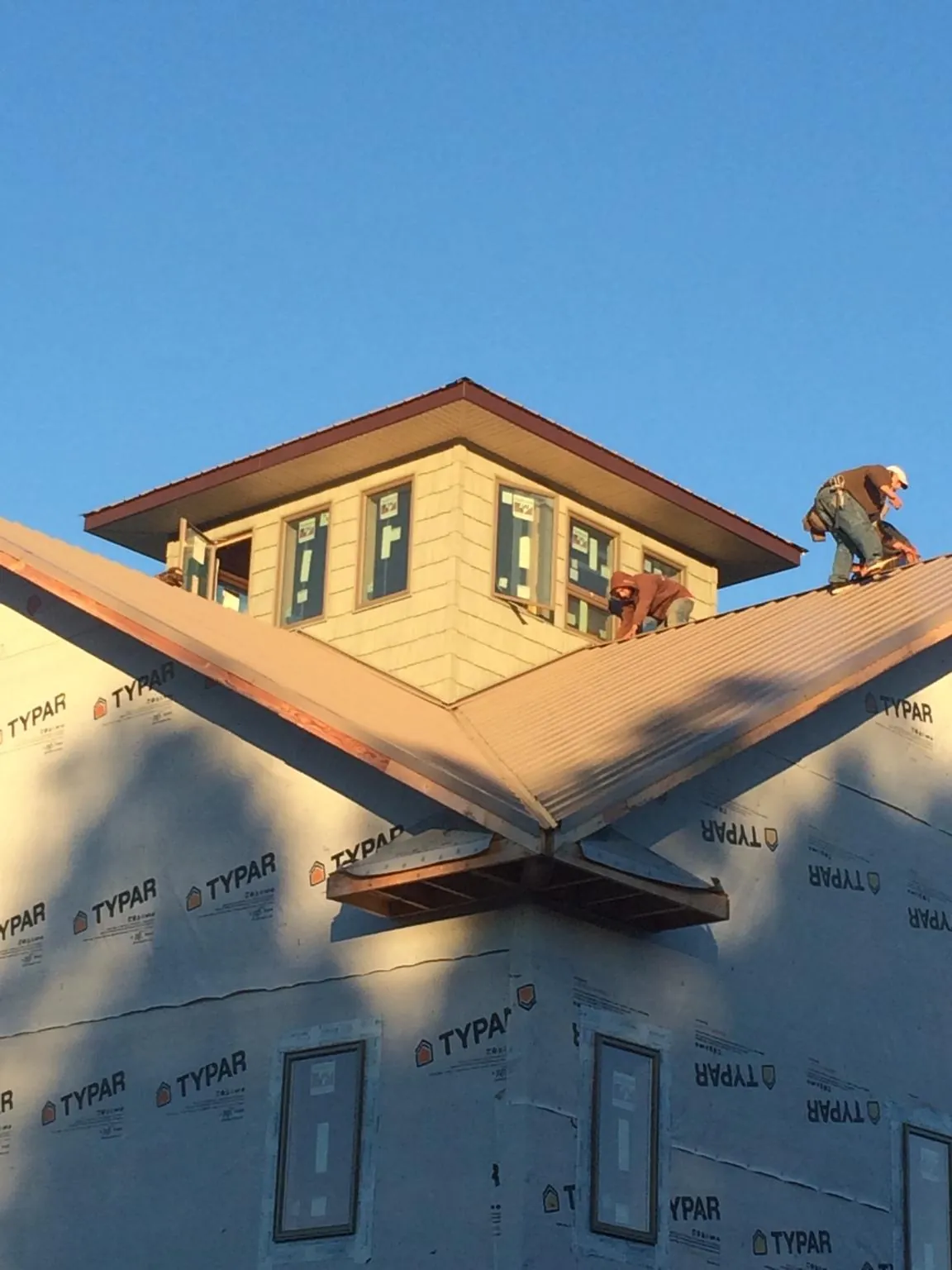 Roofers working around a rooftop cupola on a new metal roof at sunset — Roof Waterproofing in Dunlap by Roofing Brothers